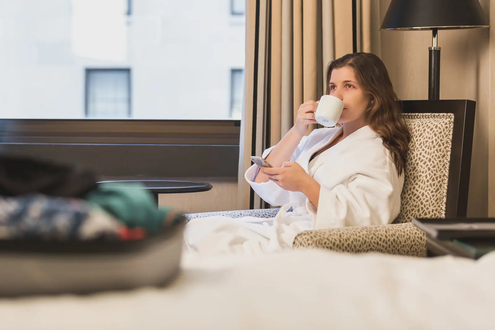A hotel guest checking her phone over morning coffee in her room